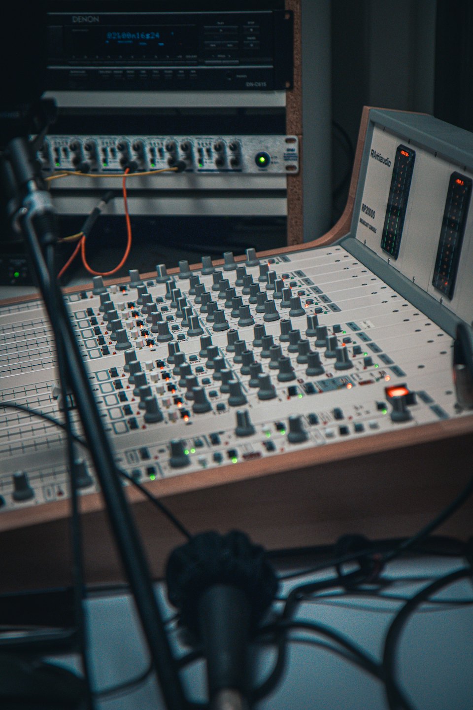 Console di missaggio audio con fader e pulsanti illuminati in uno studio.