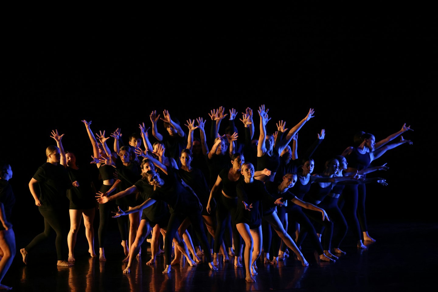 Ballerini in abiti neri eseguono una routine espressiva su un palco.